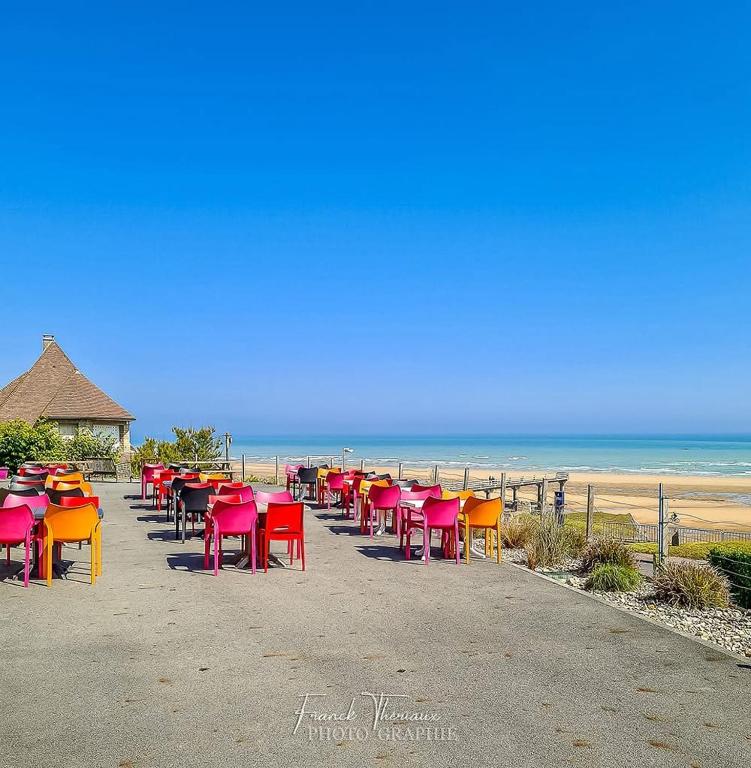a row of tables and chairs at the beach at Logis Hotel Du Casino Restaurant Le Mathelia in Vierville-sur-Mer