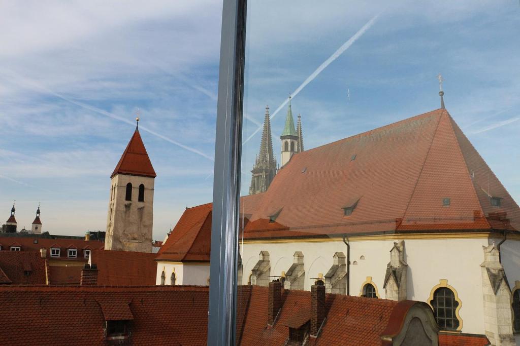 een raam met uitzicht op een gebouw met een kerk bij Ferienwohnung "Karmeliten Am Dom" in Regensburg