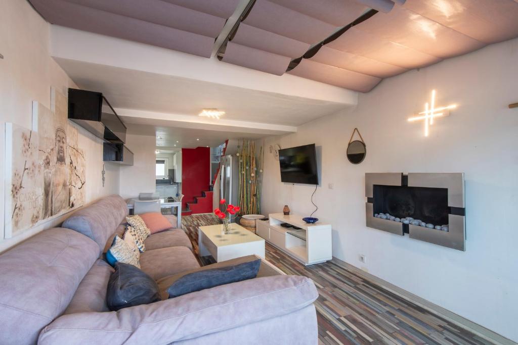 a living room with a couch and a tv at L'Anisé - Maison climatisée in Martigues