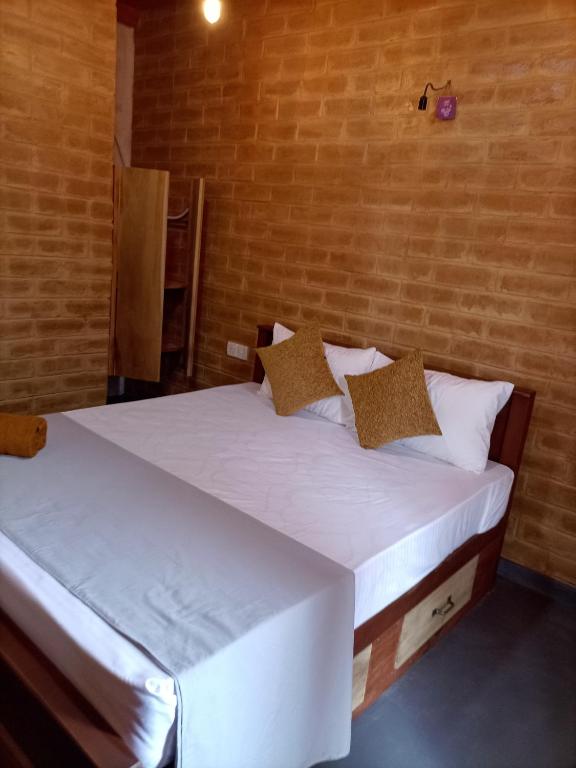 a bedroom with a bed with white sheets and pillows at DiDi Eco Home in Weligama