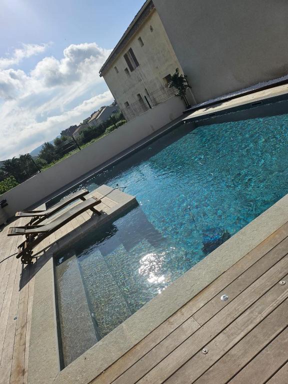 - une piscine avec des chaises sur une terrasse en bois dans l'établissement Maison d'exception au Cap Corse, à Luri