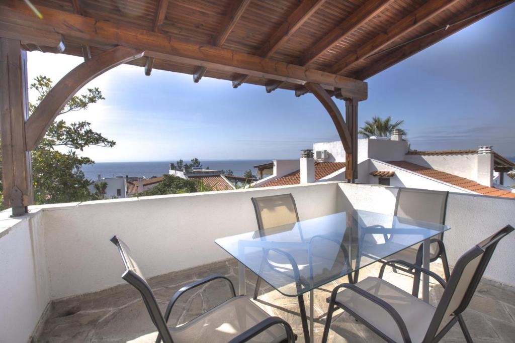 ein Tisch und Stühle auf einem Balkon mit Blick auf das Meer in der Unterkunft Eria Home by RentalsPro - Trikorfo Halkidiki in Yerakiní