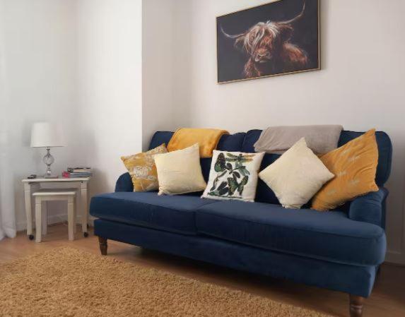 a blue couch with pillows on it in a living room at Douglas Apartment - Trains to Edin & Glasgow - Private Parking in Airdrie