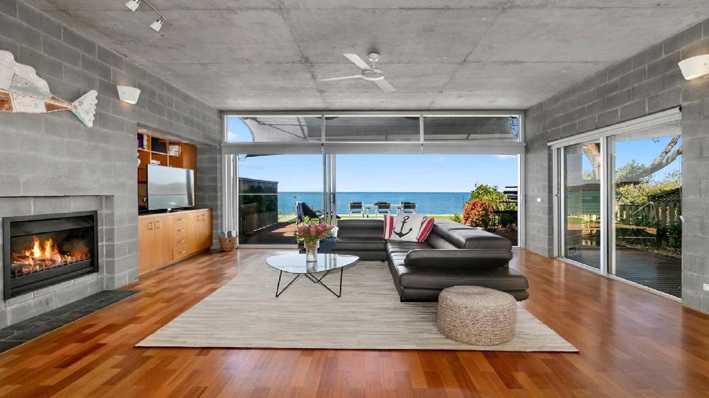 a living room with a couch and a fireplace at The Bach Pearl Beach-Absolute Beachfront , Late Check Out in Pearl Beach