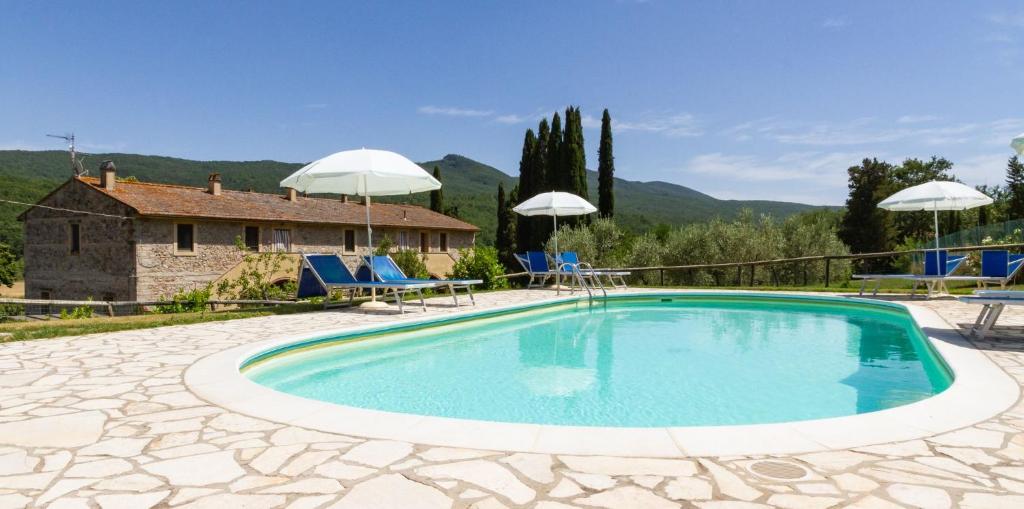 a pool with chairs and umbrellas in front of a house at Apartment with one bedroom, kitchen, bathroom Garden and shared pool in Chianni