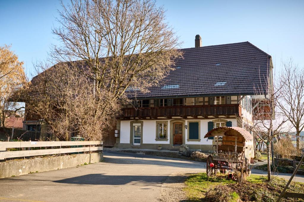 a house with a black roof on a street at Uelis-Stöckli-Gästezimmer auf Bauernhof mit Billiard und Alpakatrekking in Meikirch