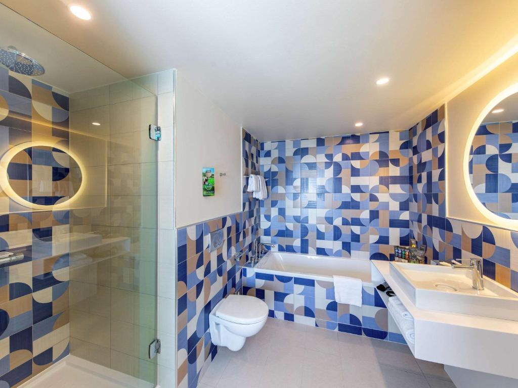 a bathroom with a toilet and a sink and a shower at Novotel Monte-Carlo in Monte Carlo