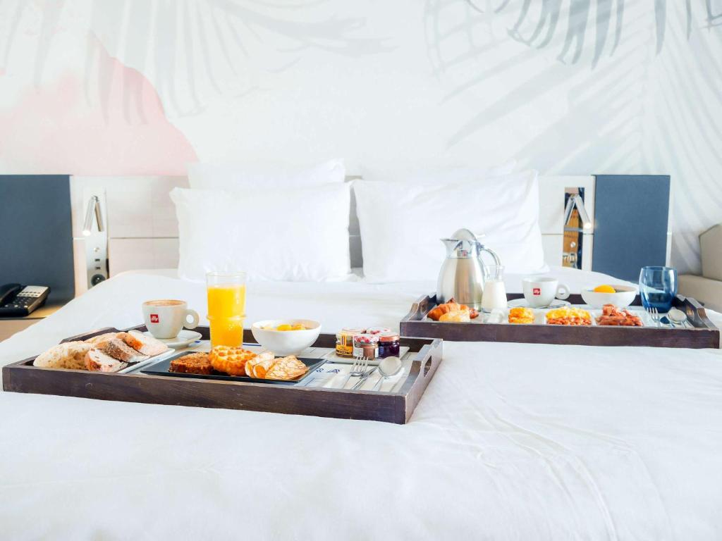 a tray of breakfast foods on a bed at Novotel Monte-Carlo in Monte Carlo
