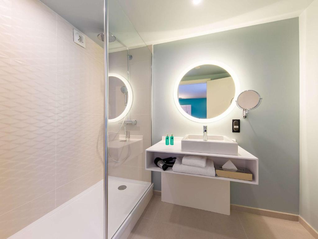 a white bathroom with a sink and a mirror at Novotel Monte-Carlo in Monte Carlo