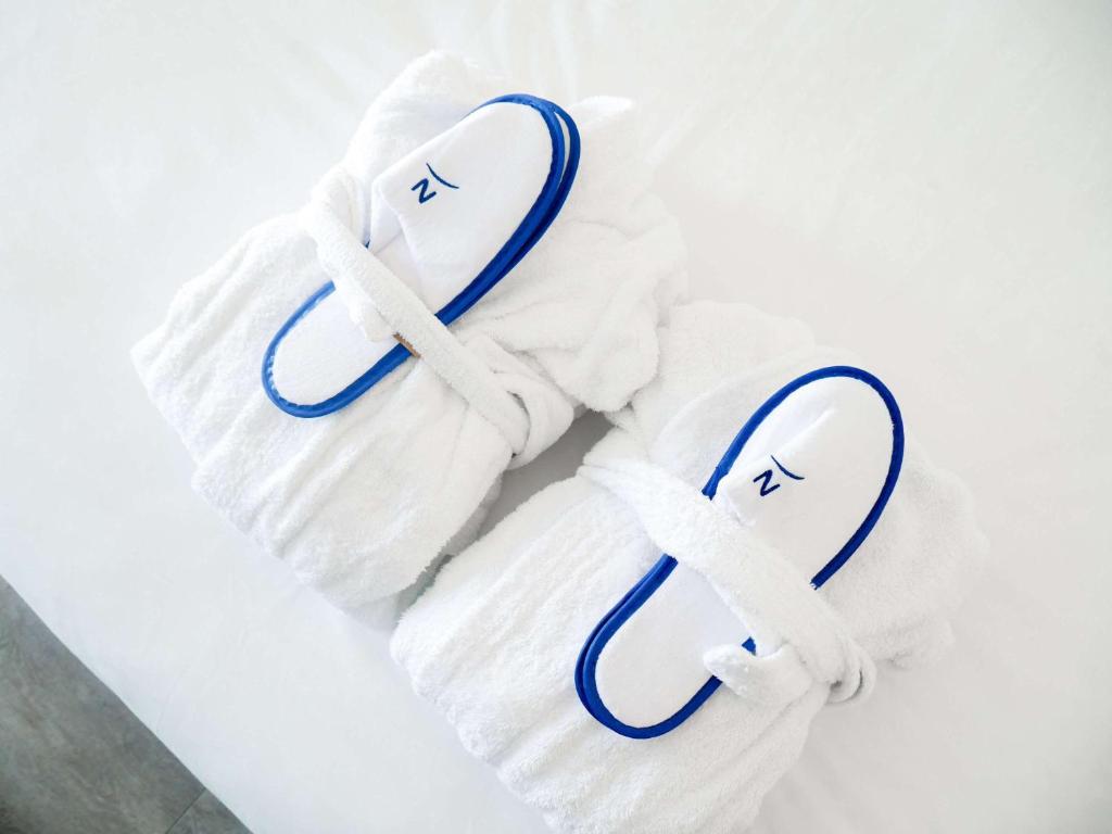 two white towels with blue handles on them at Novotel Monte-Carlo in Monte Carlo
