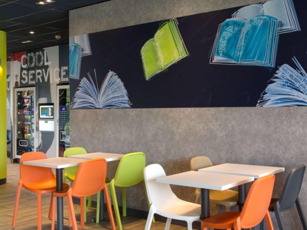 a group of tables and chairs in a restaurant at ibis budget Montceau les Mines in Montceau-les-Mines