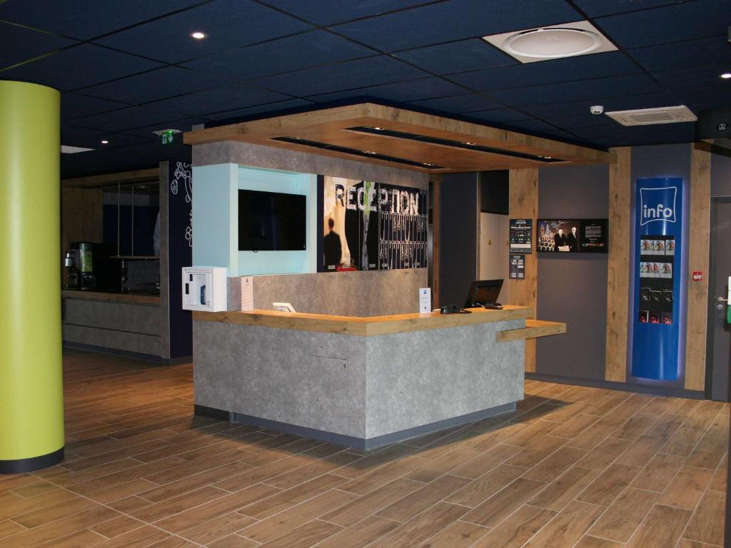 a lobby with a reception counter with a tv on it at ibis budget Montceau les Mines in Montceau-les-Mines