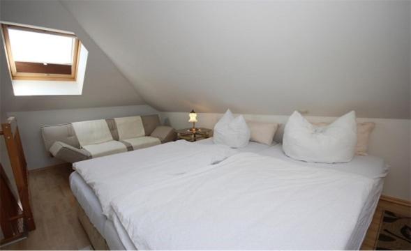 a bedroom with a white bed and a couch at Strandhaus in der Düne in Dierhagen