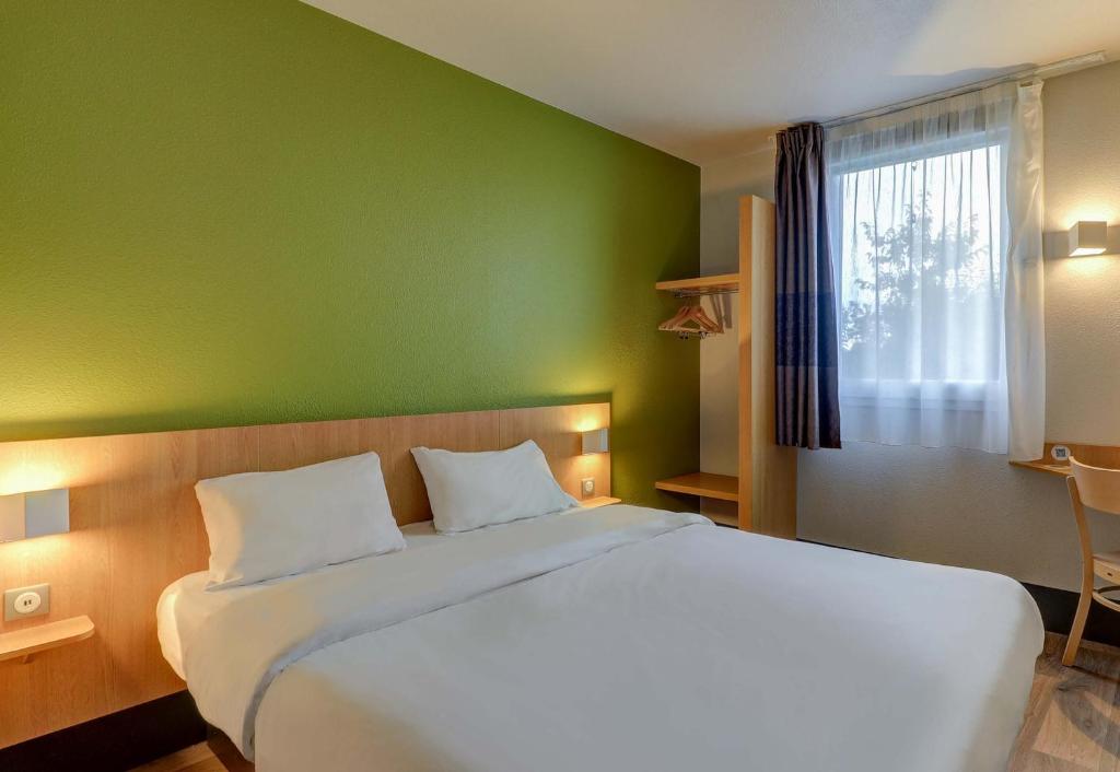 a bedroom with a white bed with a green wall at B&B HOTEL Paray-le-Monial in Paray-le-Monial