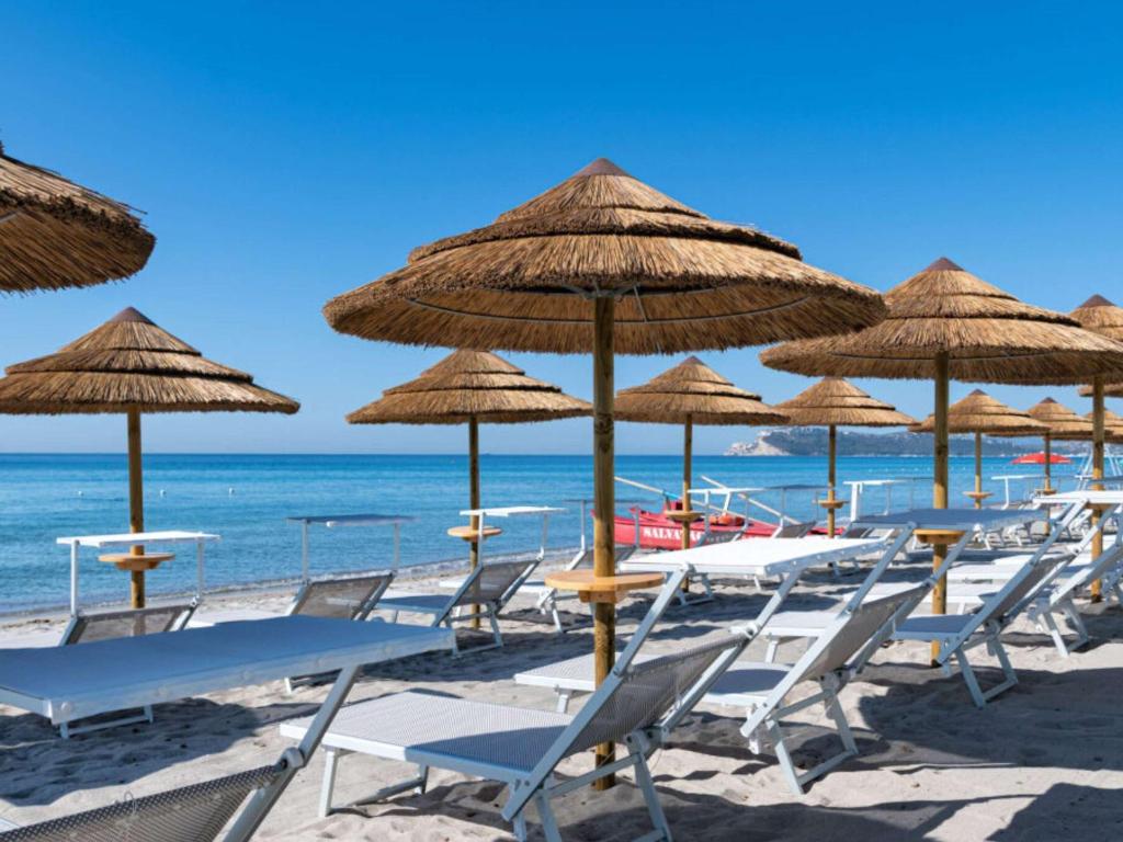 a group of chairs and umbrellas on a beach at Palazzo Tirso MGallery Cagliari in Cagliari