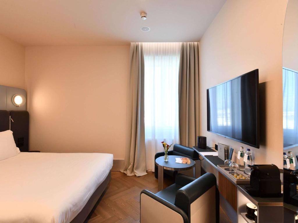 a hotel room with a bed and a desk and a television at Palazzo Tirso MGallery Cagliari in Cagliari