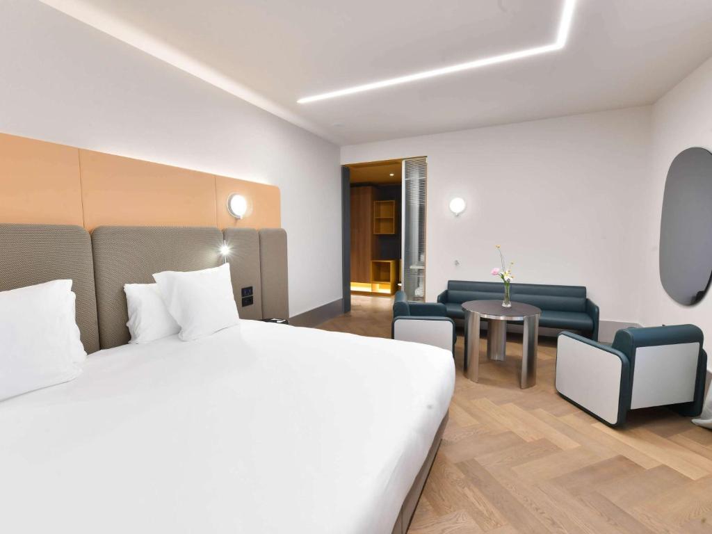 a hotel room with a bed and a couch and a table at Palazzo Tirso MGallery Cagliari in Cagliari