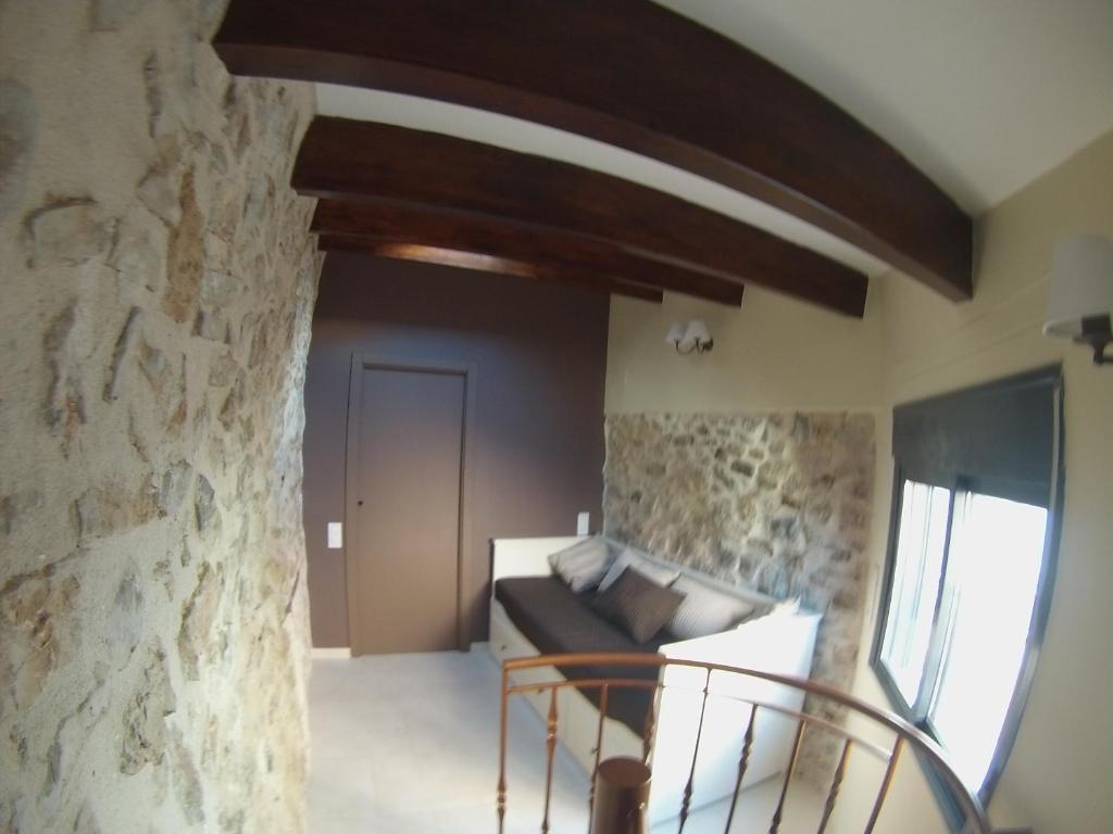 sala de estar con sofá y pared de piedra en Casa Tòful, en Alfara de Carles