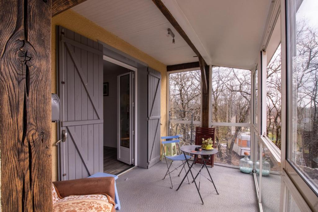 - une porte ouverte sur une terrasse couverte avec une table et des chaises dans l'établissement Maison Sur le Causse Corrézien, à Saint-Cernin-de-Larche