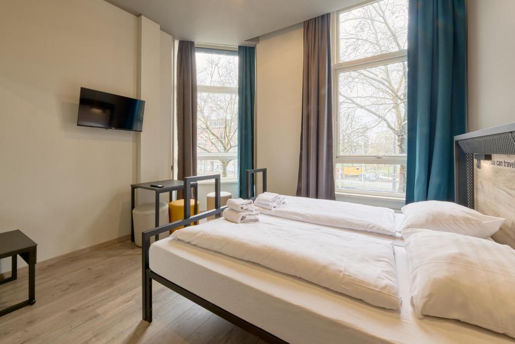 a bedroom with a large bed in front of a window at a&o Rotterdam City in Rotterdam