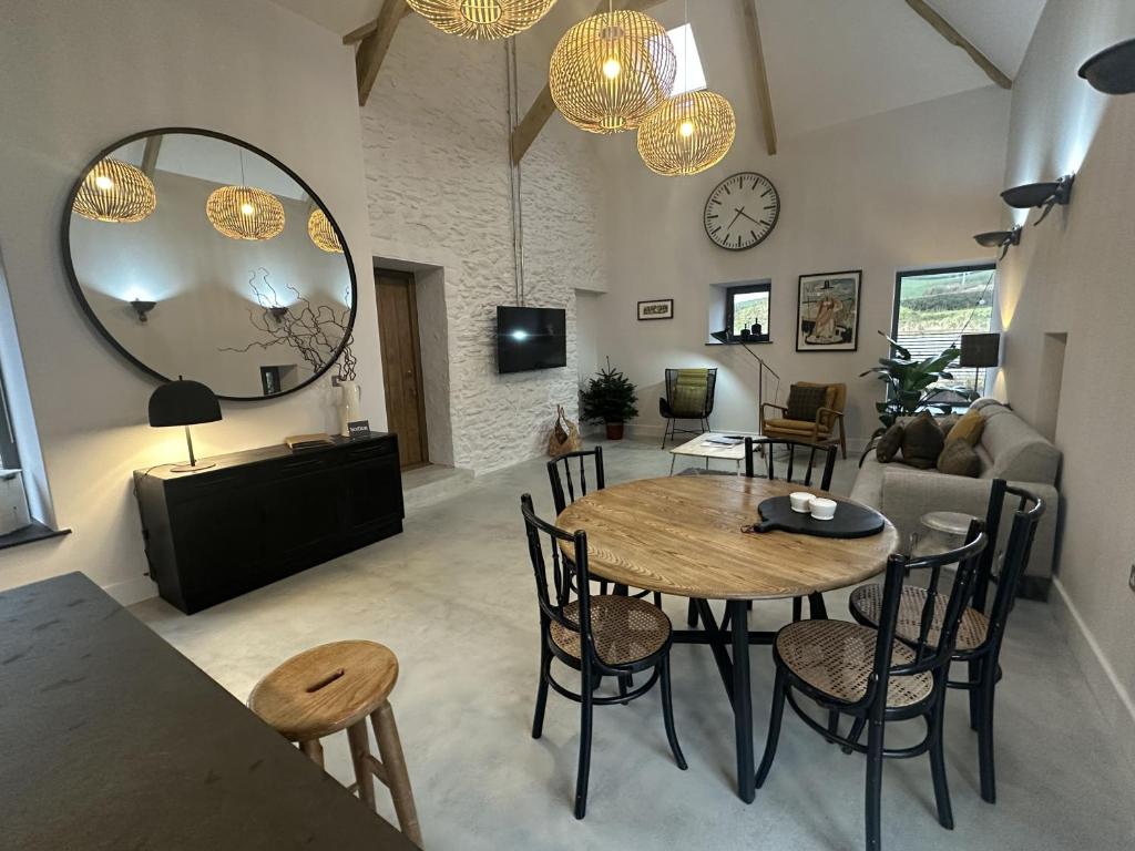 a living room with a table and chairs and a mirror at Beudy at Pentrecelyn - A stylish, dog friendly barn conversion with hot tub in Carmarthenshire in Carmarthen