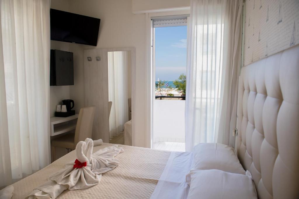 a bedroom with a white bed with a view of the ocean at Hotel ABC in Riccione