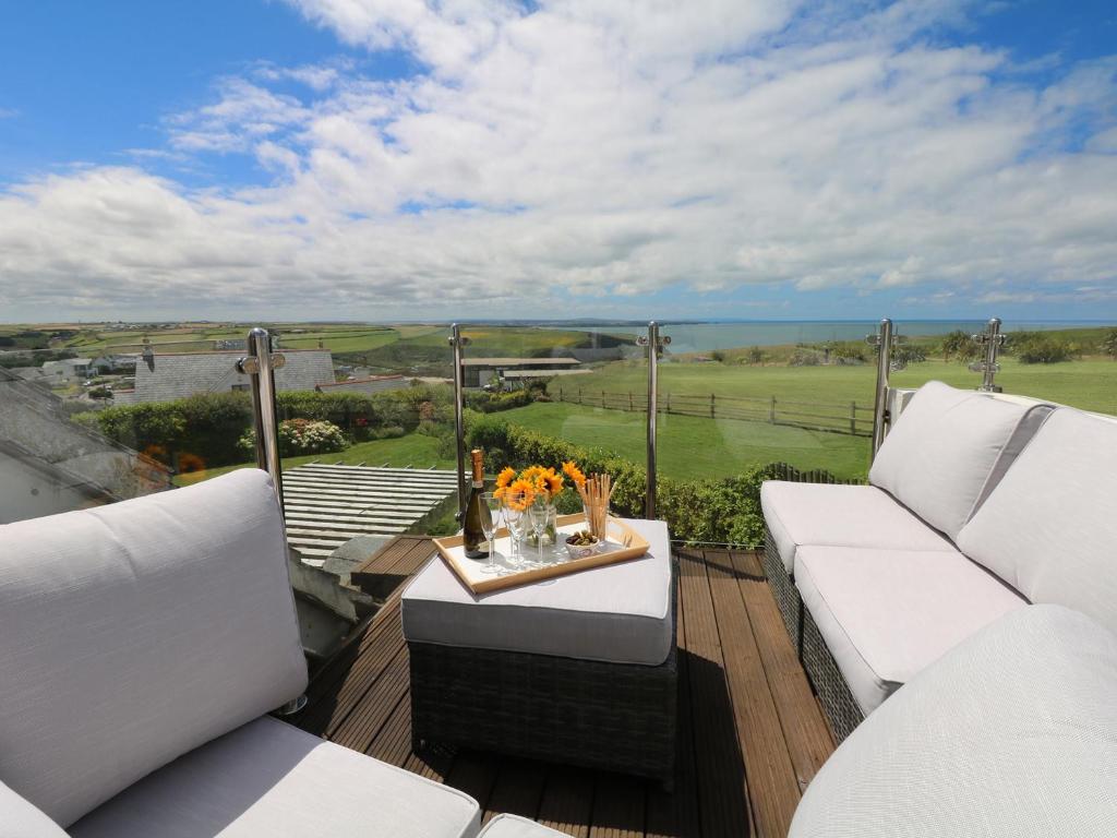a balcony with white couches and a table with flowers at Coastman's Nest in Newquay