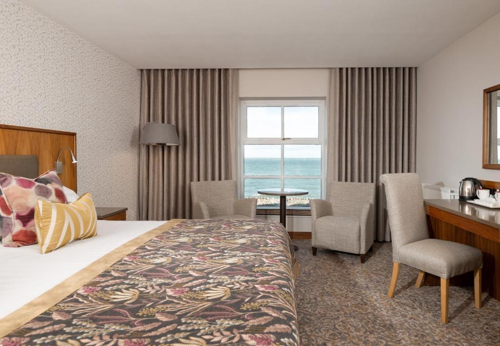 a hotel room with a bed and a table and chairs at Ballygally Castle in Larne