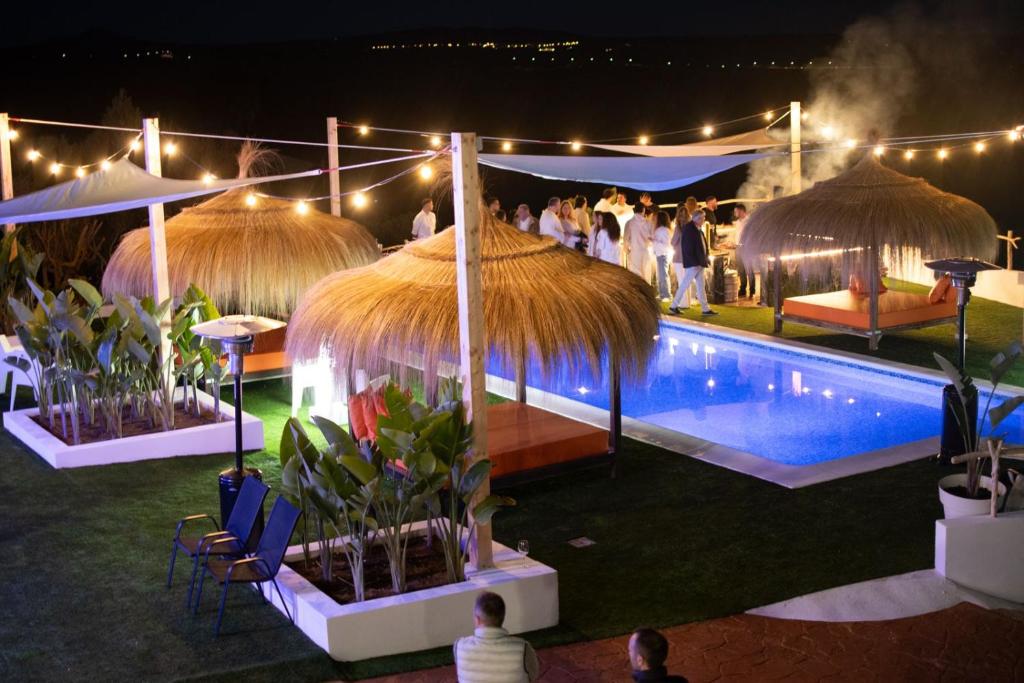 a group of people standing around a swimming pool at night at Villa Sunset Boulevard Lujo in Puntiró