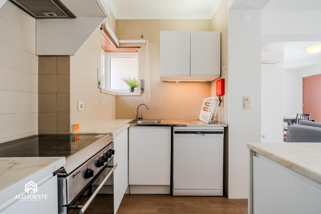 a kitchen with white cabinets and a sink at Ericeira Panoramic Sea View Apartments in Ericeira