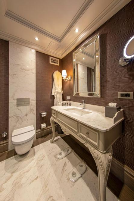 a bathroom with a sink and a toilet and a mirror at MFB Tarabya Hotel in Istanbul