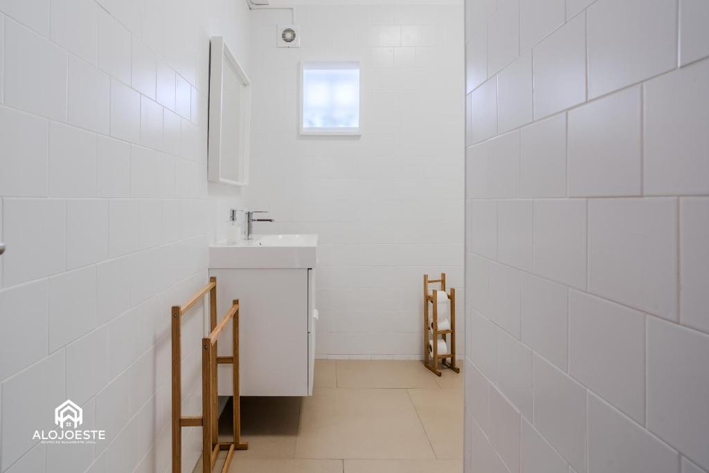 a bathroom with white tile walls and a sink at Ericeira Panoramic Sea View Apartments in Ericeira