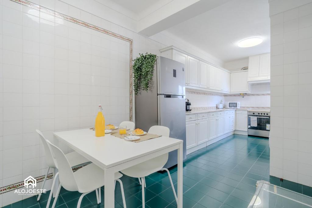 a white kitchen with a white table and chairs at Ericeira Panoramic Sea View Apartments in Ericeira