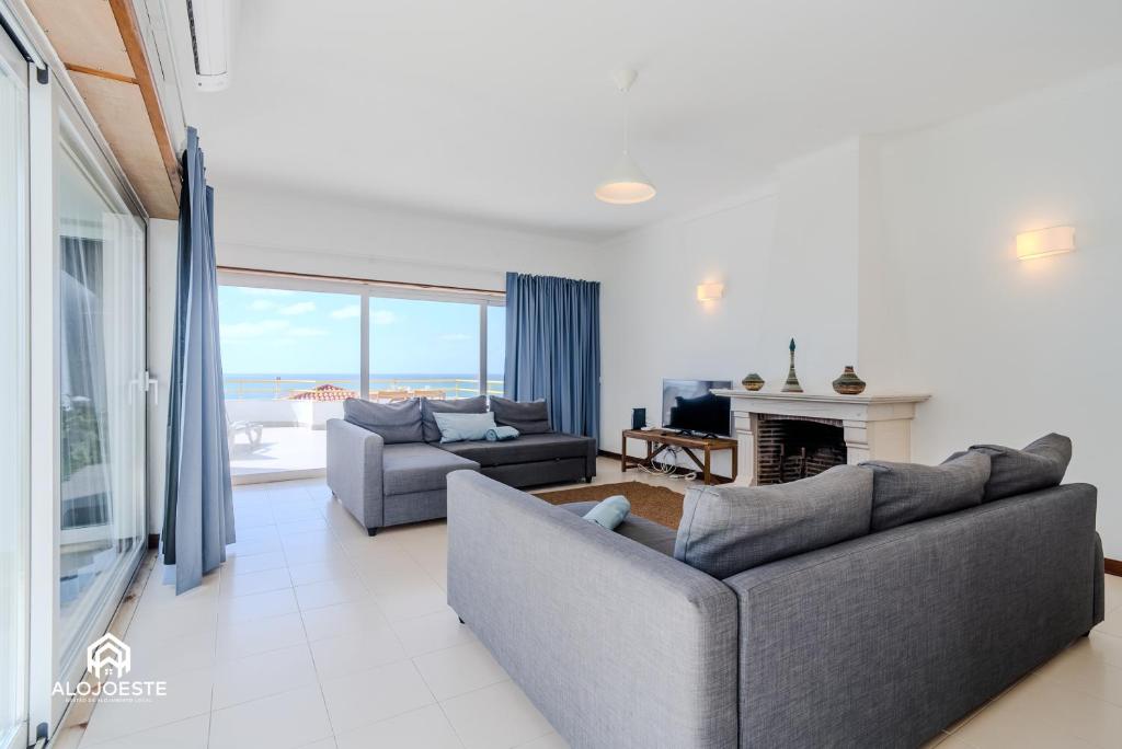 a living room with two couches and a fireplace at Ericeira Panoramic Sea View Apartments in Ericeira