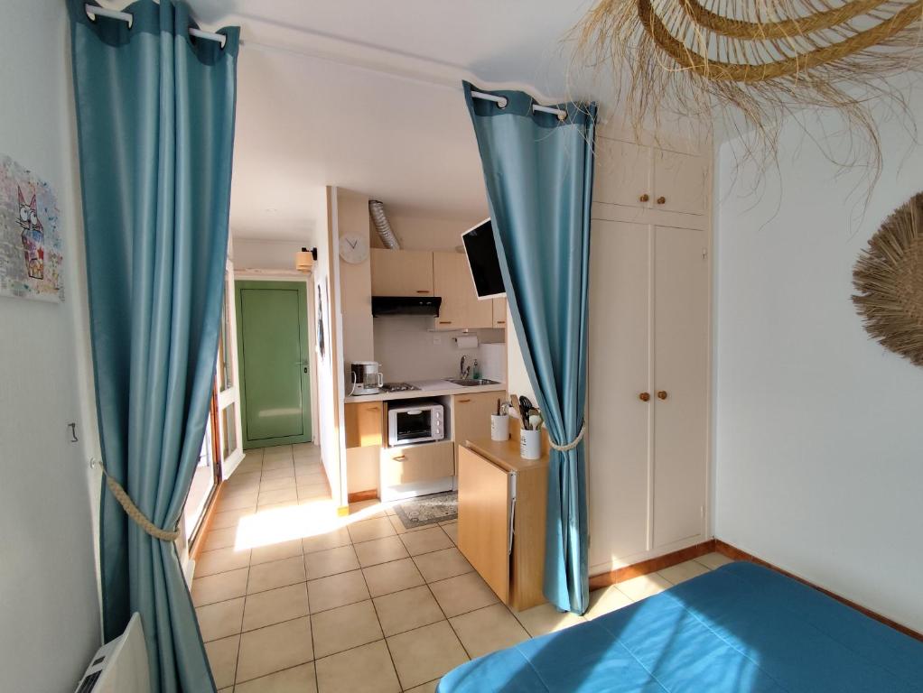 Cette chambre dispose de rideaux bleus et d'une cuisine. dans l'établissement Appartement face mer terrasse couverte parking, au Barcarès