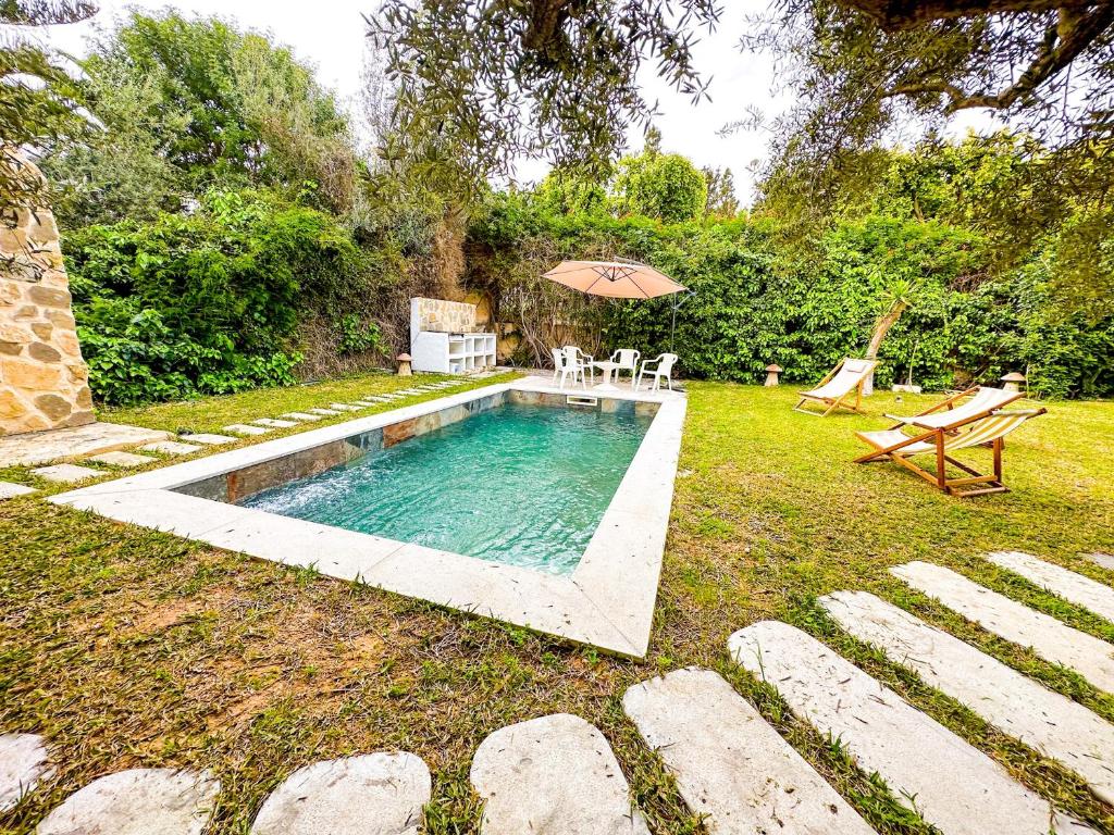 a swimming pool in a yard with an umbrella at Residence Jannet 2 Luxury Seaside 3bds in Hammamet Nord