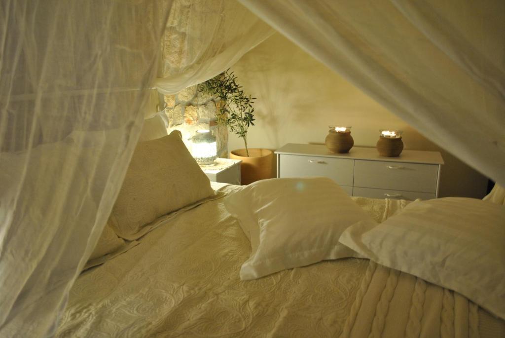 - une chambre avec un lit doté de draps et d'oreillers blancs dans l'établissement Halkidiki Luxurious Stonehouses, à Psakoudia