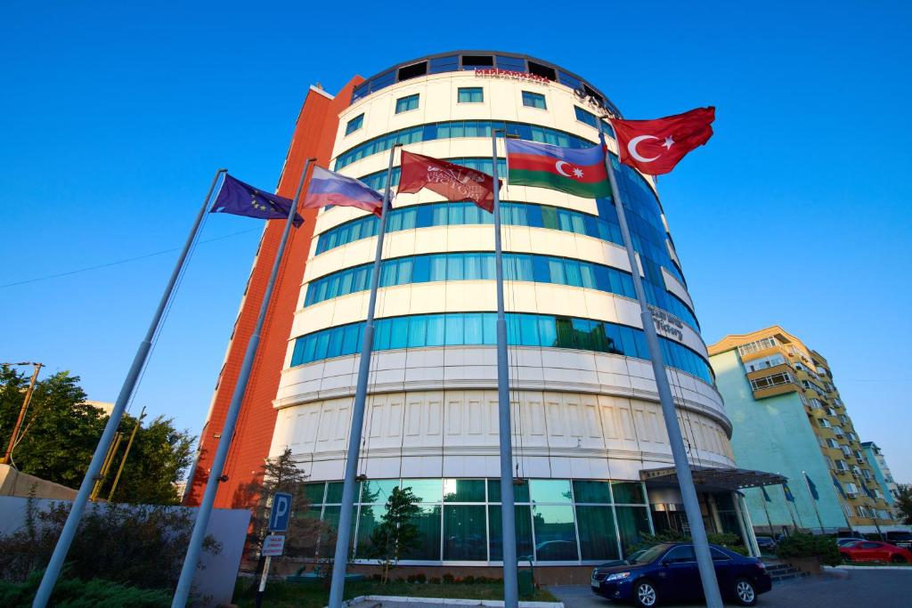 a building with three flags in front of it at Grand Hotel Victory in Aktau