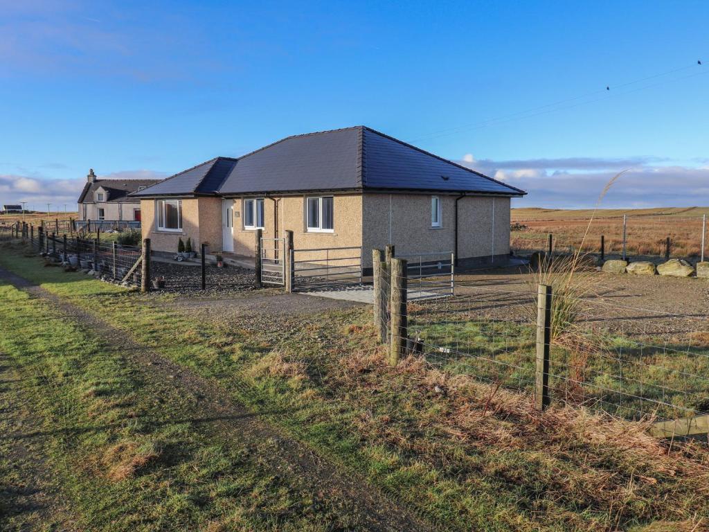 a house in a field next to a fence at Lapwing Cottage in Howmore