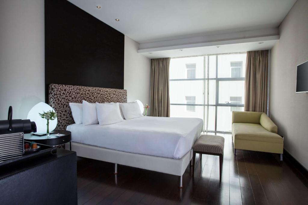 a bedroom with a large white bed and a chair at NH Collection Buenos Aires Centro Histórico in Buenos Aires