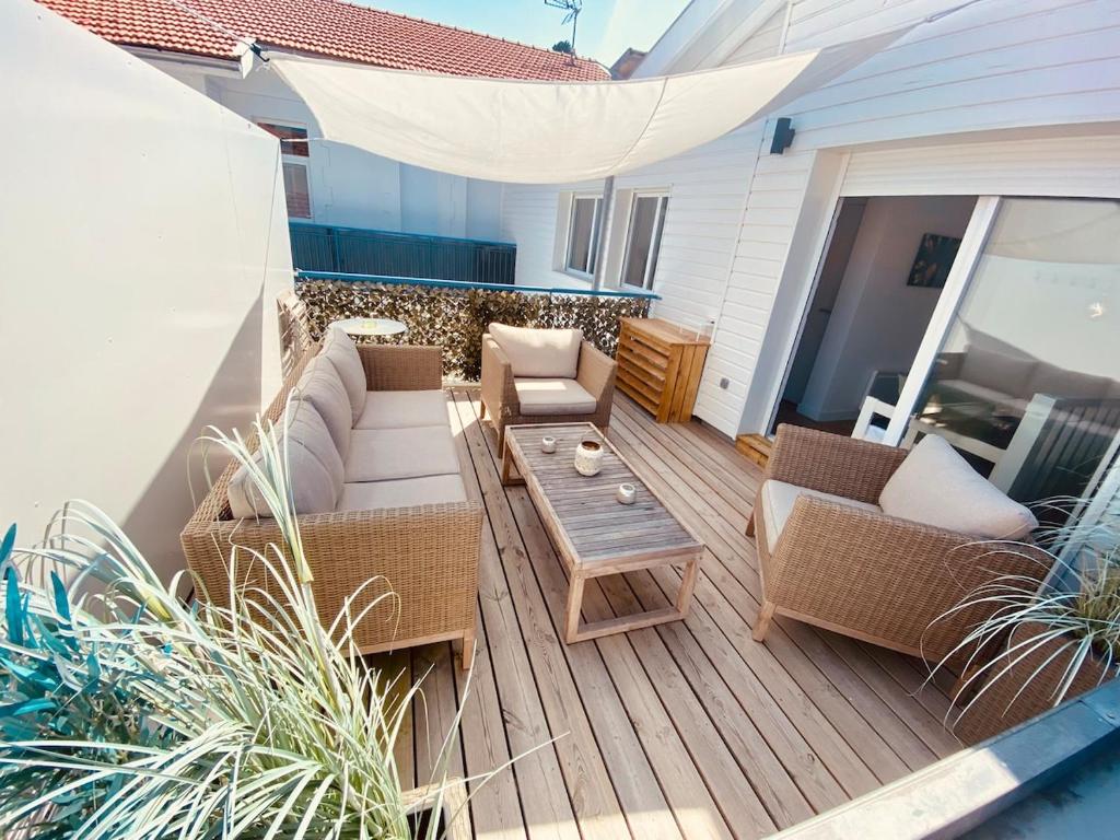 un patio avec des canapés et une table sur une terrasse dans l'établissement Le petit Desbiey, à Arcachon
