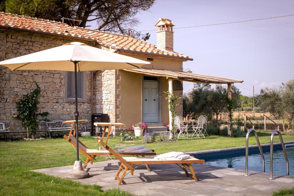 un patio con mesa y sombrilla junto a la piscina en Villa Il Nido, en Cortona