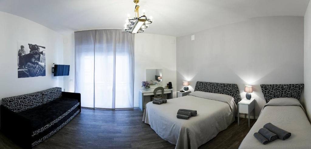 ラヴェンナにあるB&B Corso Diazのベッドルーム1室(ベッド2台、ソファ、窓付)
