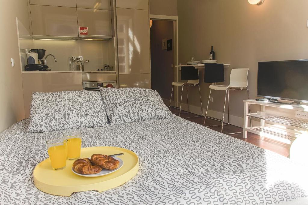 BmyGuest - Cardosas Stylish Apartment في بورتو: سرير مع صينية من الدونات وكأسين من عصير البرتقال