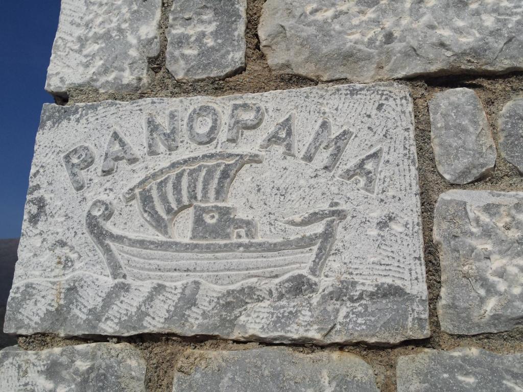 una señal de piedra en una pared con un barco. en Panorama Rooms en Pyrgos Dirou