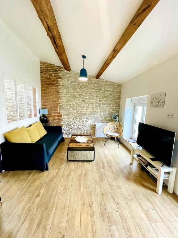 - un salon avec un canapé bleu et un mur en briques dans l'établissement L'Atelier - Coeur de ville, à La Rochelle