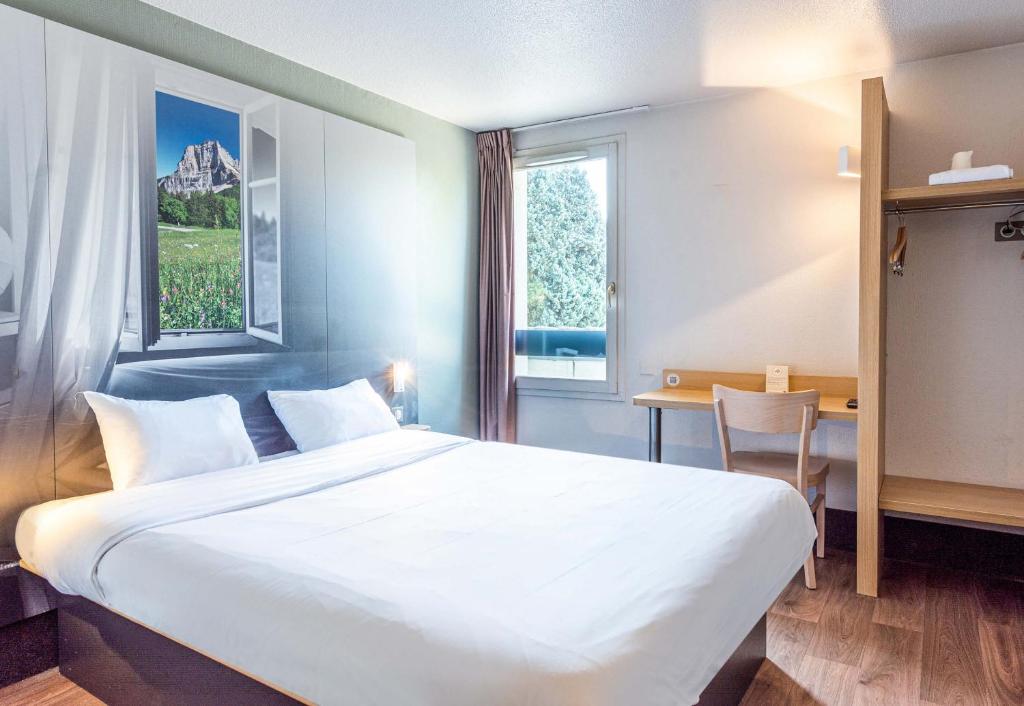 シャンベリにあるB&amp;B HOTEL CHAMBERY La Cassineの大きなベッドと机があるホテルの部屋