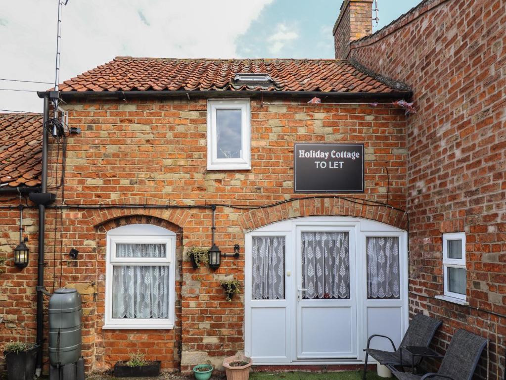 a brick building with a white door and a sign at The Old Stables in Skegness