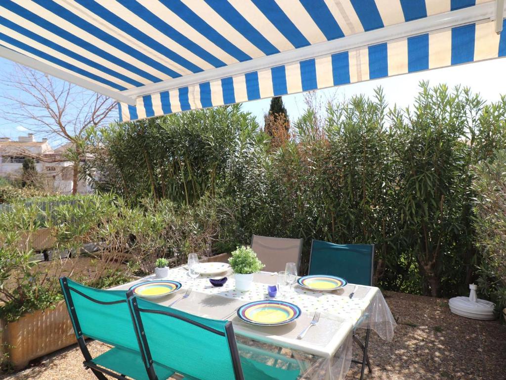 une table et des chaises sous un parapluie bleu et blanc dans l'établissement Studio Cabine 4 pers RDC avec Piscines, Terrasse, Proche Mer et Commerces - FR-1-307-36, au Grau-du-Roi