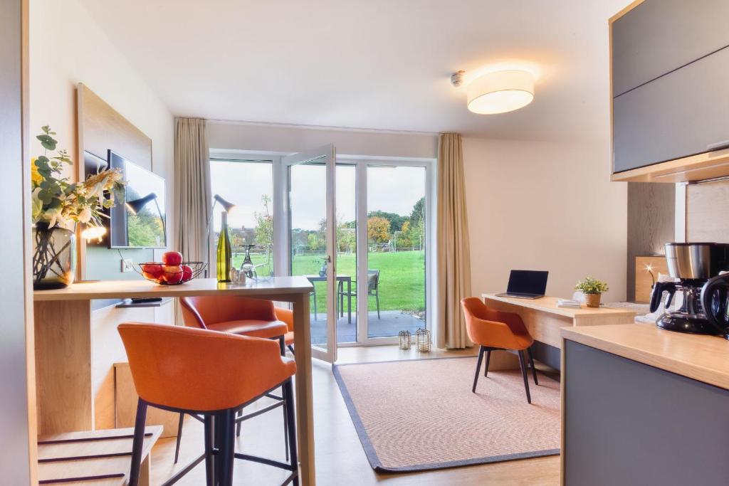 a kitchen with orange chairs and a table with a counter at Ferienwohnung Waldkauz 23 im Wreecher Idyll Rügen by ruyastay in Putbus